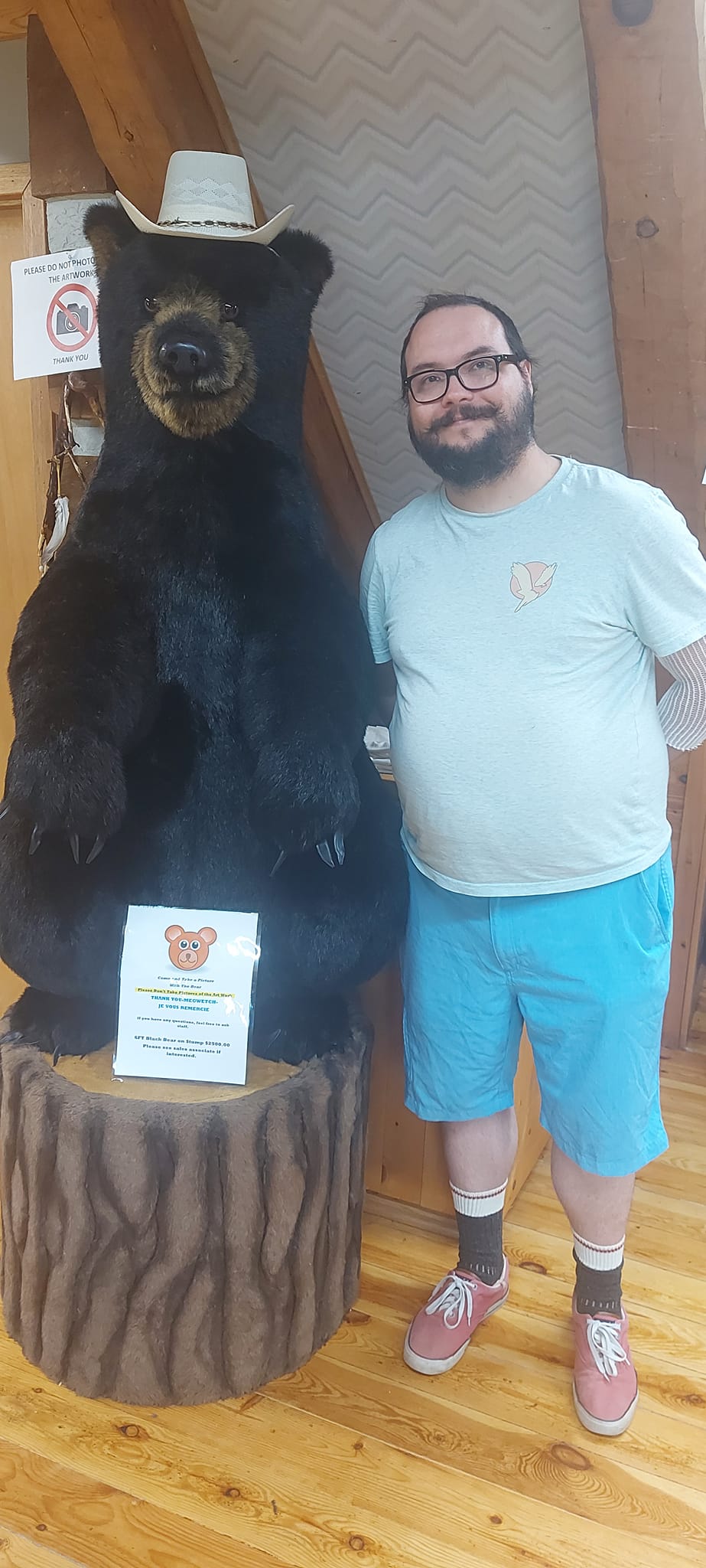 A man short hair and bushy facial hair stands next to a smaller bear statue